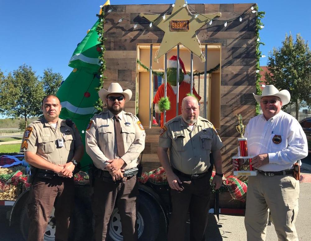 Sheriff holding first place trophy and deputies standing in front of float 